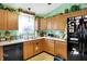 Well-lit kitchen featuring a black dishwasher, double sink, and wooden cabinetry at 1307 Estuary Dr, Indianapolis, IN 46217