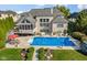 Aerial view of the backyard pool and patio with umbrella table and lounge chairs by the brick home at 13499 Marjac Way, Fishers, IN 46055