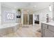 Spacious bathroom with soaking tub, glass shower enclosure, decorative window, and doorway into the bedroom at 13499 Marjac Way, Fishers, IN 46055