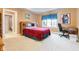 Cozy bedroom with a red quilt, a window that allows natural light, and a desk in the corner at 13499 Marjac Way, Fishers, IN 46055
