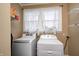 Bright laundry room featuring a washer, dryer, window with white curtains, and shelving for organized convenience at 2141 E County Road 200 N, Danville, IN 46122