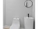 Contemporary bathroom with a round mirror, sleek toilet, and pedestal sink with a modern faucet at 2406 Carrollton Ave, Indianapolis, IN 46205