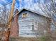 This home's exterior features weathered siding, a brick chimney, and mature trees at 3132 E 36Th St, Indianapolis, IN 46218