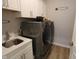 Spacious laundry room features modern gray appliances, sink, white cabinets for storage, and wood look vinyl floors at 488 Ehrlich Ln, Westfield, IN 46069