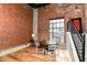 Dining room with exposed brick, wood floors, large windows, and a modern staircase at 735 Lexington Ave # 30, Indianapolis, IN 46203