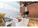Cozy living room features exposed brick, wood floors, modern sectional sofa, and a large television at 735 Lexington Ave # 30, Indianapolis, IN 46203
