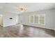Bright living room with wood-look flooring, a ceiling fan, a white door and large windows at 8015 Sargent Rdg, Indianapolis, IN 46256