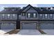 Gray townhome exterior featuring a three-car garage, dark trim, and modern design at 9730 Behner Dr, Fishers, IN 46250