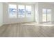 Bright living room with light wood floors, and three large windows overlooking the community at 9730 Behner Dr, Fishers, IN 46250