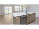 Kitchen island with white countertops and stainless steel dishwasher, adjacent to a sliding glass door and large windows at 9742 Behner Dr, Fishers, IN 46250