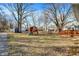 Backyard view featuring a deck, playset, picnic table, sheds, and mature trees at 1195 W Edgewood Ave, Indianapolis, IN 46217