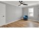 This bedroom features a light hardwood floor, a light ceiling fan, and a blue chair near the window at 1195 W Edgewood Ave, Indianapolis, IN 46217