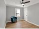 Well-lit bedroom with a ceiling fan, light hardwood floors and a blue armchair by the window at 1195 W Edgewood Ave, Indianapolis, IN 46217