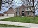 Traditional brick two-story home with arched entry, three-car garage, manicured lawn, and mature trees at 15050 Bainbridge Ct, Westfield, IN 46074
