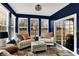 Cozy sunroom with two chairs, ottoman, natural light, and sliding doors to a backyard view at 1684 Hedley W Way, Avon, IN 46123
