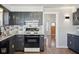 Kitchen with dark gray cabinets, white backsplash, modern appliances, an open doorway and wood floor creating an open feel at 2022 Newton St, Columbus, IN 47201