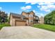 View of the tan home with a two-car garage, a basketball hoop, a well-manicured lawn, and a covered porch with an American flag at 211 Deborah Ln, Whiteland, IN 46184