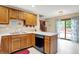 Well-lit kitchen boasts wood cabinets, white counters, a stainless steel sink, and access to a deck at 211 Deborah Ln, Whiteland, IN 46184