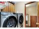 Laundry room with modern stainless steel front loading washer and dryer and overhead wood cabinets at 211 Deborah Ln, Whiteland, IN 46184