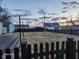 View of backyard with wooden deck, black fence, and string lights at sunset at 2441 Northview Ave, Indianapolis, IN 46220