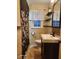 Bathroom featuring tiled walls, modern sink, floral shower curtain and updated fixtures at 2441 Northview Ave, Indianapolis, IN 46220