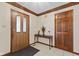 Inviting foyer with a wooden door with glass, and a wood table with decorative flowers at 252 N Raceway Rd, Indianapolis, IN 46234