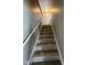 Carpeted staircase with handrail leads to the upper level, illuminated by overhead lighting and natural light at 3060 S Lyons Ave, Indianapolis, IN 46241