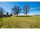 Grassy backyard featuring mature trees and a partial view of the sports fields nearby at 3932 Villa Dr, Columbus, IN 47203