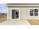 Backyard concrete patio area with a sliding glass door and window with light colored siding at 632 Derek Ln, Trafalgar, IN 46181