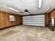 Bright garage featuring ample space, garage door, wood paneling, and storage shelves at 812 Madison St, Frankton, IN 46044