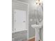 Stylish powder room features a sleek pedestal sink, modern fixtures, and a round mirror at 9730 Prairie Smoke Dr, Noblesville, IN 46060