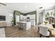 Bright, open kitchen featuring white cabinets, a large island with seating, stainless steel appliances, and wood flooring at 1004 Astor Ln, Carmel, IN 46032
