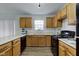 A bright kitchen with wood cabinets, black appliances, plenty of counterspace, and wood floors at 10046 Gate Dr, Indianapolis, IN 46239