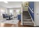 Elegant dining room with modern table set, blue accent cabinet, and staircase featuring gray carpet at 12486 Schoolhouse Rd, Fishers, IN 46037