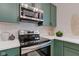 Close-up of the kitchen features stainless steel oven and microwave with matching green cabinets at 1434 S Talbott St, Indianapolis, IN 46225