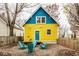 Backyard featuring gravel, a seating area, and a charming yellow house with blue accents at 1647 N Tacoma Ave, Indianapolis, IN 46218