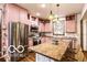 Modern kitchen with stainless steel appliances, pink cabinets, decorative backsplash and a center island with seating at 1647 N Tacoma Ave, Indianapolis, IN 46218
