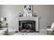 Living room fireplace with white mantle, black tile, decorative art, and a round coffee table at 1805 Braeburn Dr, Carmel, IN 46032