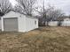 Detached one car garage with white siding and grey door with mature trees at 1843 Bauer Rd, Indianapolis, IN 46218