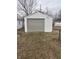 Detached one car garage with white siding and grey door surrounded by trees at 1843 Bauer Rd, Indianapolis, IN 46218
