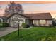 Charming single-Gathering home featuring a manicured lawn, attached garage, and brick accents under a colorful sunset at 2020 Cross Willow Ln, Indianapolis, IN 46239