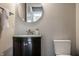 Bathroom featuring dark vanity with glass countertop, round mirror, and sleek fixtures at 2274 Finchley Rd, Carmel, IN 46032