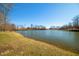 Beautiful lake view with a grassy shoreline and mature trees under a clear blue sky at 2688 S Oscar Ct, Morgantown, IN 46160