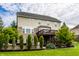 View of the back of a two-story home featuring a deck, manicured landscaping, and a retaining wall at 3905 Pelham Rd, Carmel, IN 46074