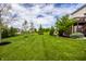 Expansive backyard featuring lush green lawn, mature trees, and a charming deck on the home's rear at 3905 Pelham Rd, Carmel, IN 46074