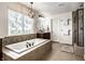 Bright bathroom featuring a soaking tub with stone accents and a separate glass-enclosed shower at 3905 Pelham Rd, Carmel, IN 46074