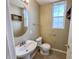 Modest bathroom with toilet, pedestal sink, and mirror, complemented by a window at 3941 Planewood Dr, Indianapolis, IN 46235
