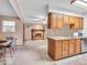 Open-concept view of the kitchen with wood cabinets, a breakfast bar, and seamless transition to the living room at 504 Pelenor Dr, Franklin, IN 46131