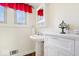 Bright bathroom featuring a pedestal sink, medicine cabinet, and red window treatments at 5055 Willow Rd, Zionsville, IN 46077