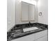 A well-lit bathroom featuring a black marble countertop, black faucet, white sink, and gold-trimmed mirror at 6311 Feather Run Dr, Indianapolis, IN 46237
